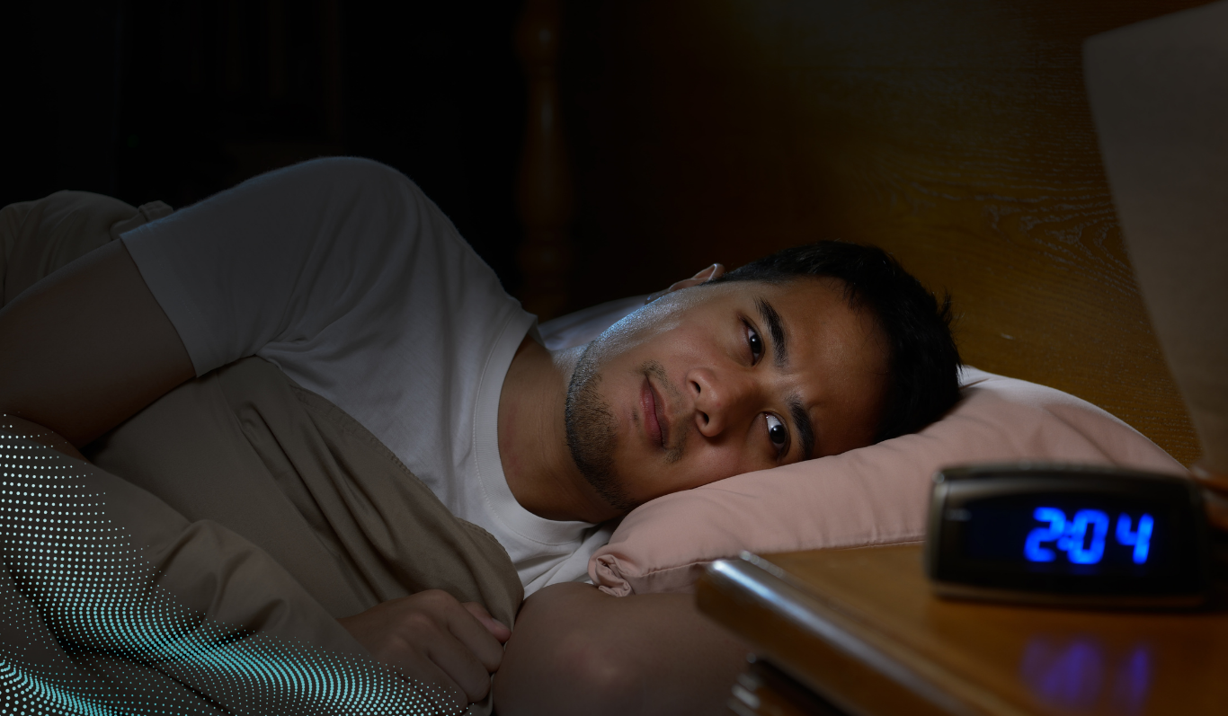 A man is looking at his alarm clock in the middle night as he is struggling to sleep