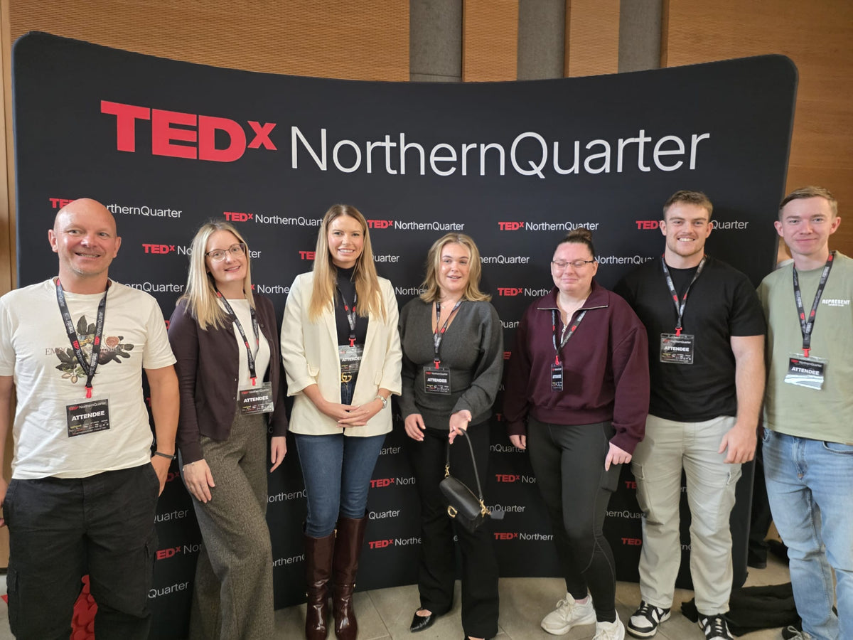 The PEAK4 team standing together in front of the TEDxNorthernQuarter backdrop at Stoller Hall, Manchester