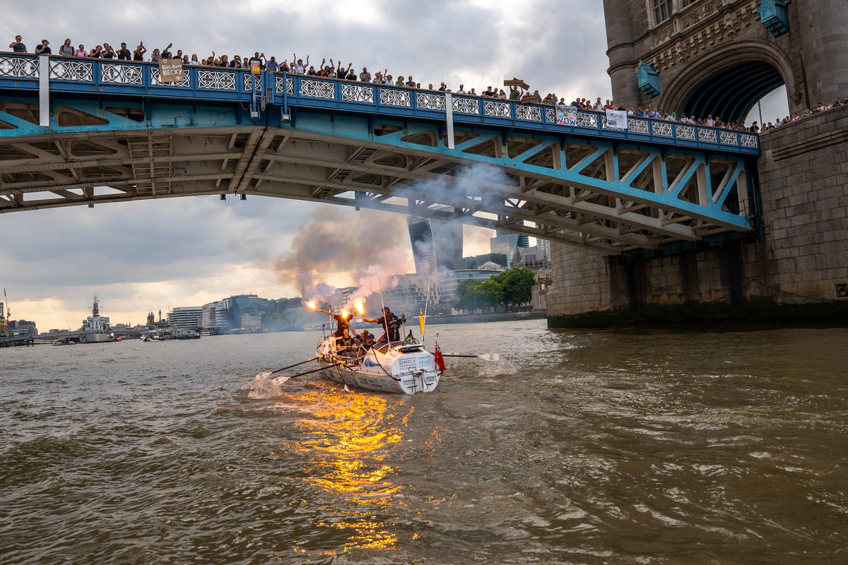 Team Nautilus passing under Tower Bridge with flares and crowds watching from the bridge above